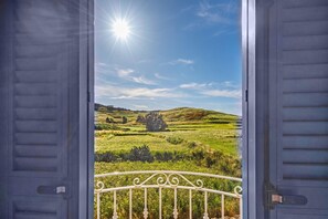 An open balcony with a metal railing, overlooking a green landscape with rolling hills and a clear sky. - Dar Sara Holiday Gozitan Home (Victoria)