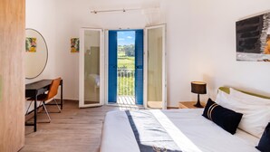 A bedroom with a bed, a desk, and a chair. There is a door leading to a balcony with a blue shutter. - Dar Sara Holiday Gozitan Home (Victoria)