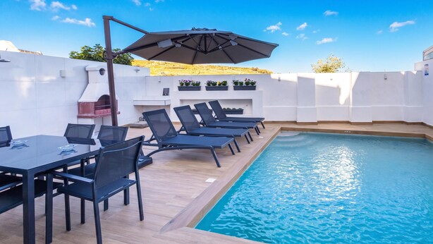 A poolside area with a dining table, chairs, and a barbecue grill. - Dar Sara Holiday Gozitan Home (Victoria)