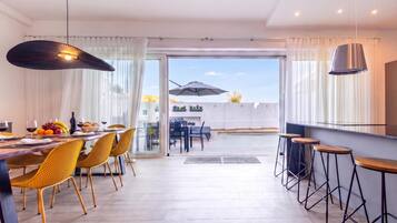 A modern dining area with a table set for two, yellow chairs, and a bar with stools.