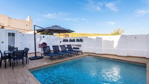 A swimming pool with lounge chairs and a table, surrounded by a white wall and a clear sky. - Dar Sara Holiday Gozitan Home (Victoria)