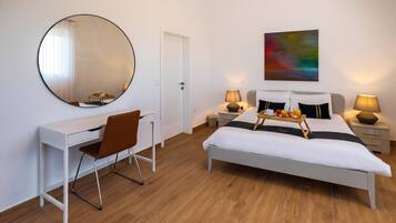 A modern bedroom with a bed, bedside tables, a desk, a chair, and a large mirror.