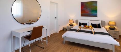 A modern bedroom with a bed, bedside tables, a desk, a chair, and a large mirror.