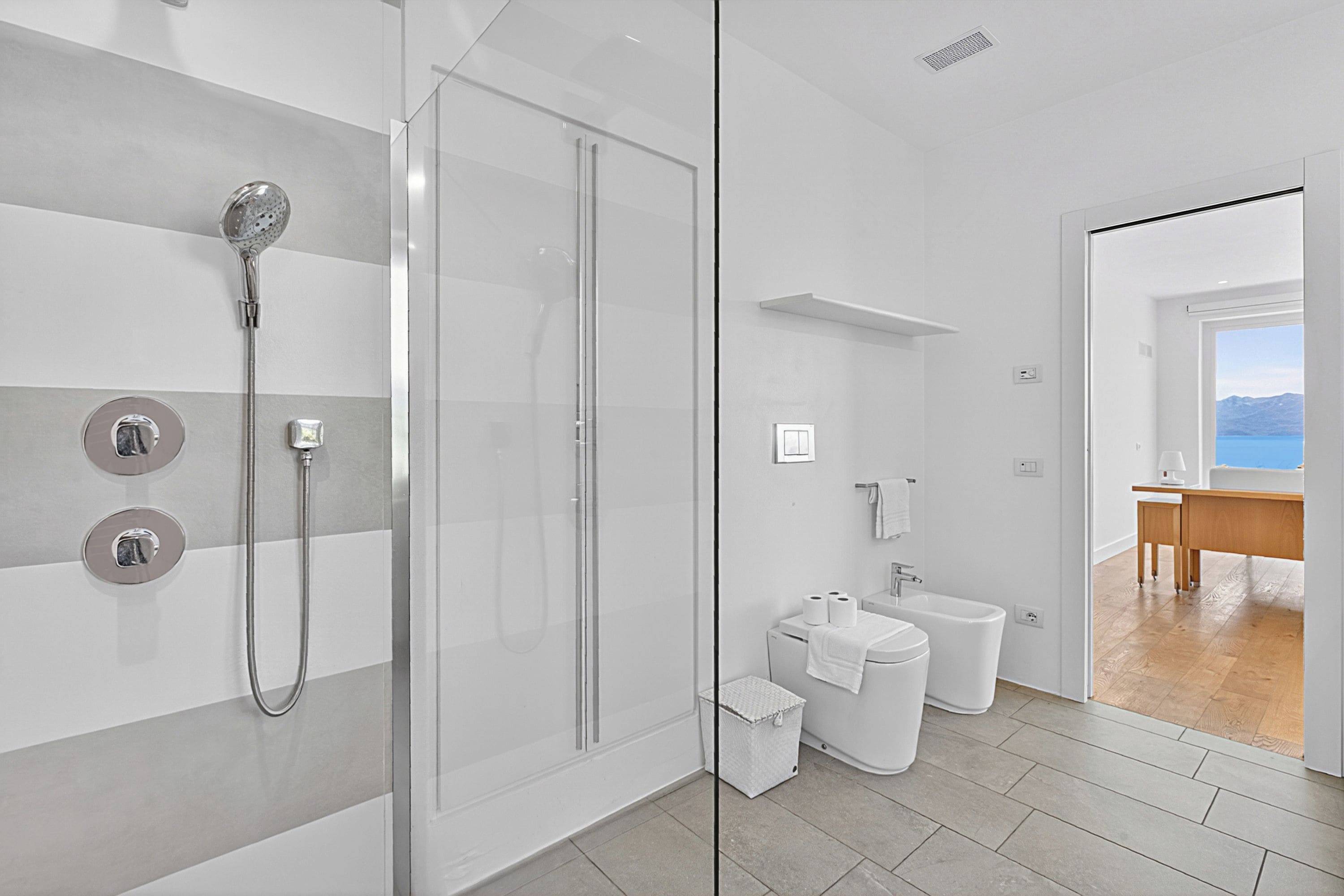 Un baño moderno con ducha acristalada, inodoro, bidé y lavamanos.