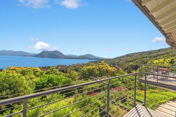 A balcony with a view of a lake, mountains, and greenery. - Villa Alessia - 4 bed Villa With Lake Maggiore View (Stresa)