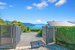 A paved pathway leading to a gated entrance with a view of a lake and mountains. - Villa Alessia - 4 bed Villa With Lake Maggiore View (Stresa)