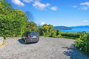 A car parked on a cobblestone driveway with a scenic view of mountains and a lake. - Villa Alessia - 4 bed Villa With Lake Maggiore View (Stresa)