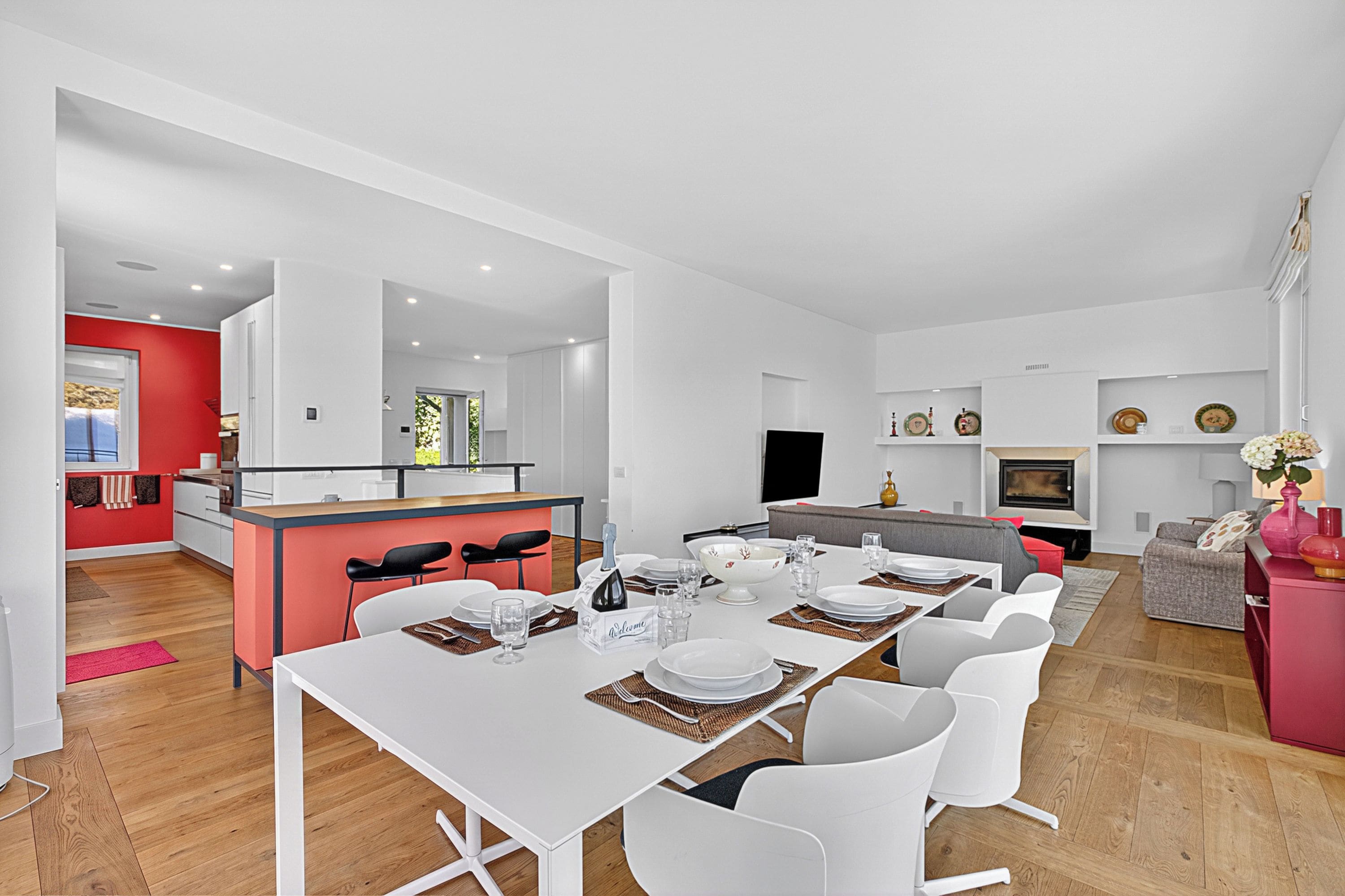 Un espacio habitable moderno con comedor, cocina y una pared de acento roja.