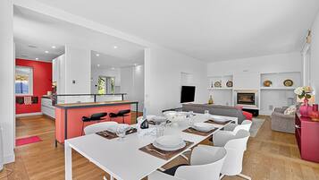 Un espacio habitable moderno con comedor, cocina y una pared de acento roja.