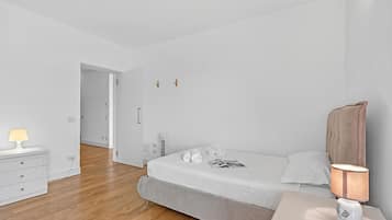 A modern bedroom with a bed, bedside table, lamp, and a dresser.
