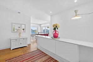 A modern kitchen with white cabinetry, a striped rug, a pink vase, and a view of mountains through large windows. - Villa Alessia - 4 bed Villa With Lake Maggiore View (Stresa)