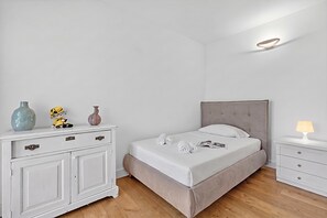 A bedroom with a bed, bedside tables, a dresser, and decorative items. - Villa Alessia - 4 bed Villa With Lake Maggiore View (Stresa)