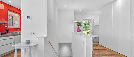 A modern interior with a kitchen, a staircase, and a hallway leading to a room with a view.
