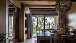 A dining area with a large window, wicker furniture, and a hanging light fixture.