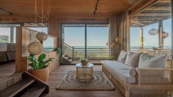 Un interior de madera con un sofá, una mesa de centro y vistas al mar.