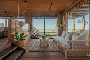 Un interior de madera con un sofá, una mesa de centro y vistas al mar.