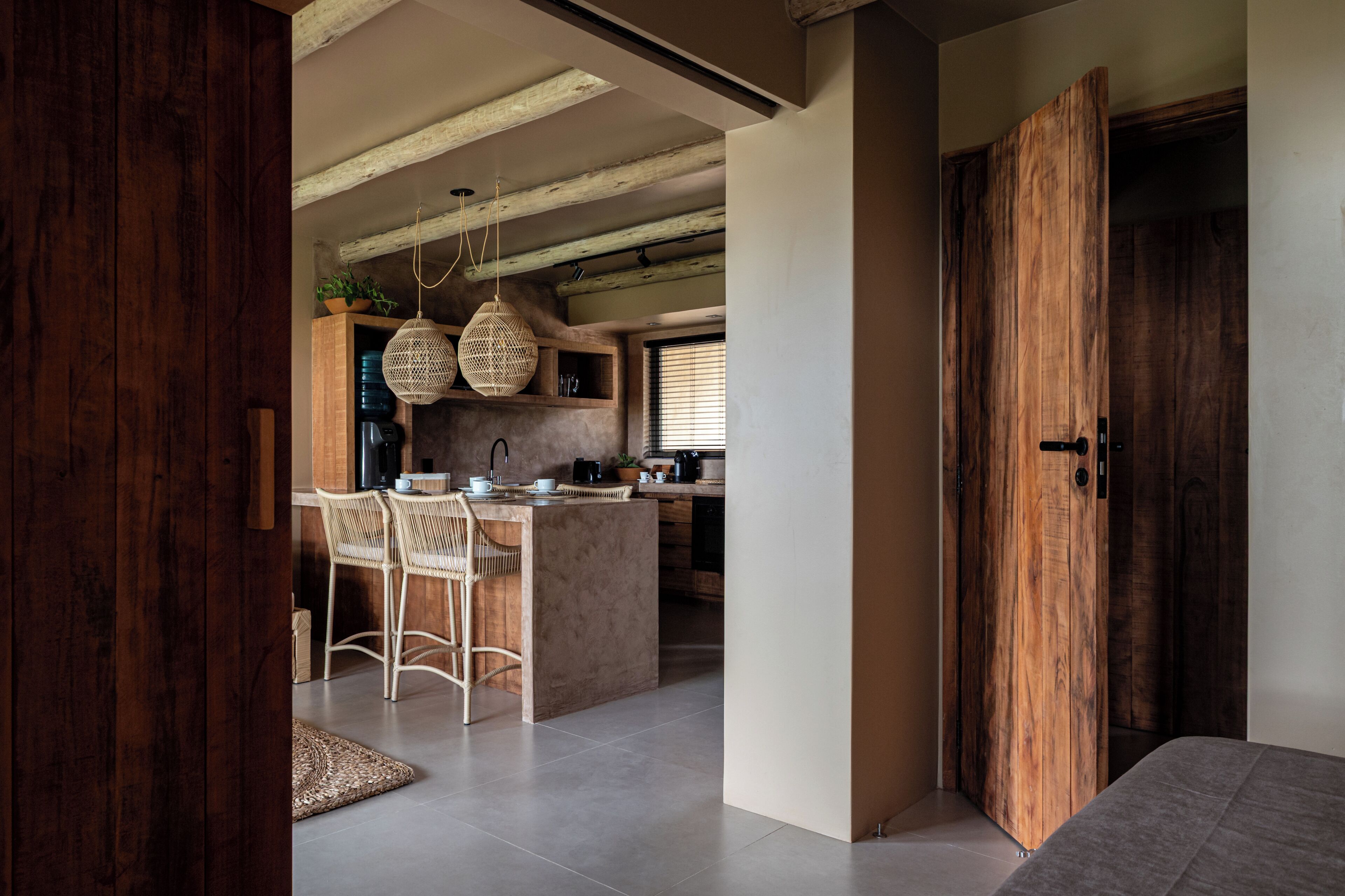 A modern kitchen with a central island, wooden beams, and a large wooden door.