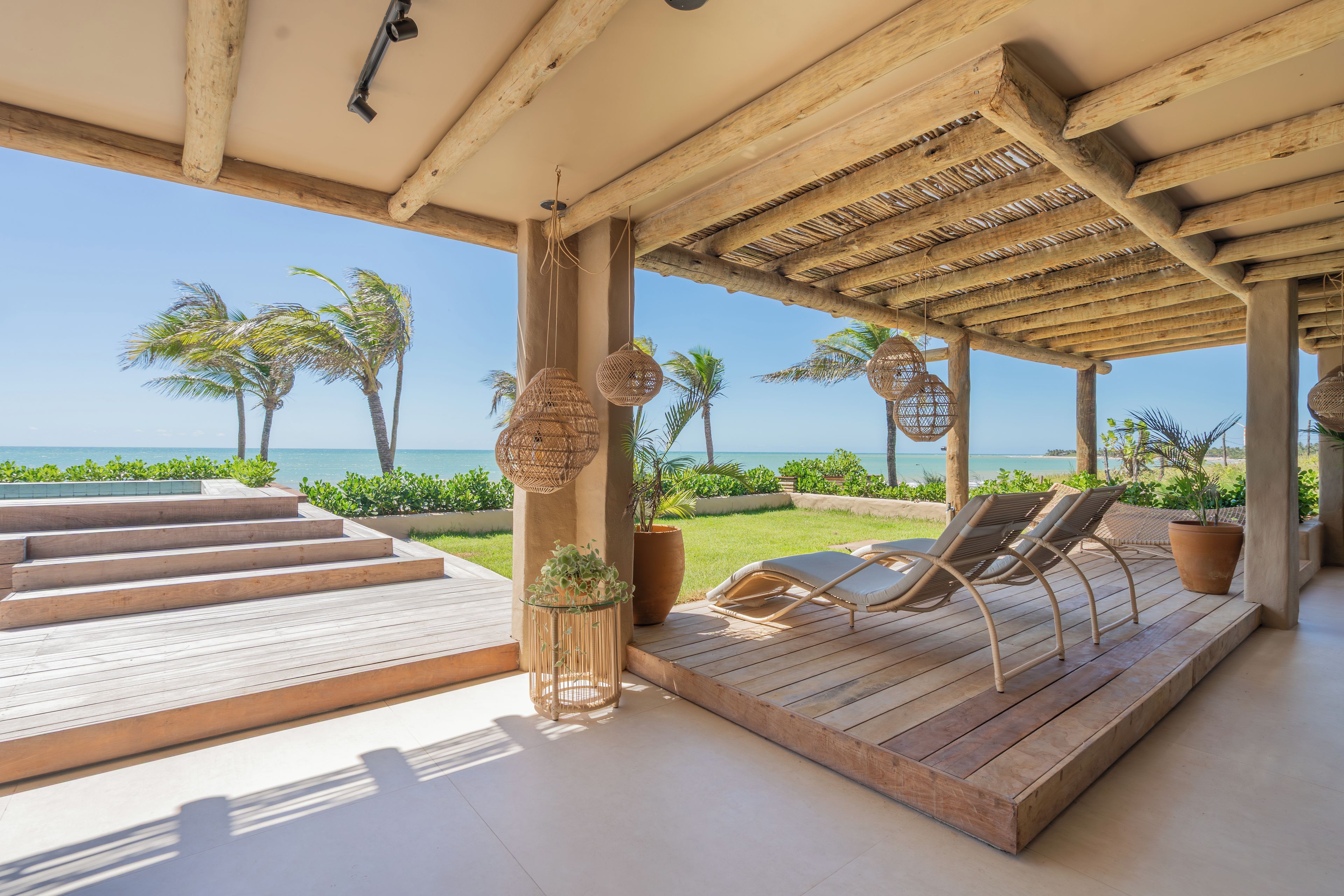 Une terrasse en bois avec des chaises longues et vue sur l’océan.