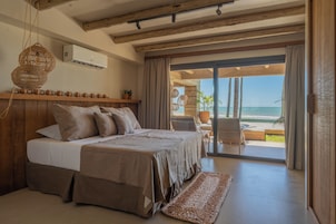 Un dormitorio con cama, ventana con cortinas, ventilador de techo y vista al océano.