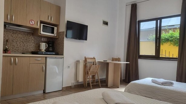 Habitación de hotel con dos camas, kitchenette, televisor y ventana con vistas.