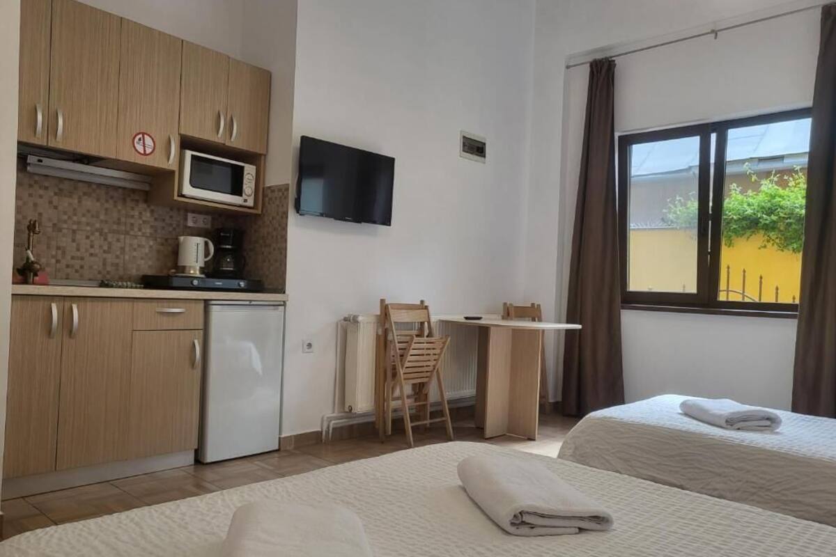 Een hotelkamer met twee bedden, een kitchenette, een televisie en een raam met uitzicht.