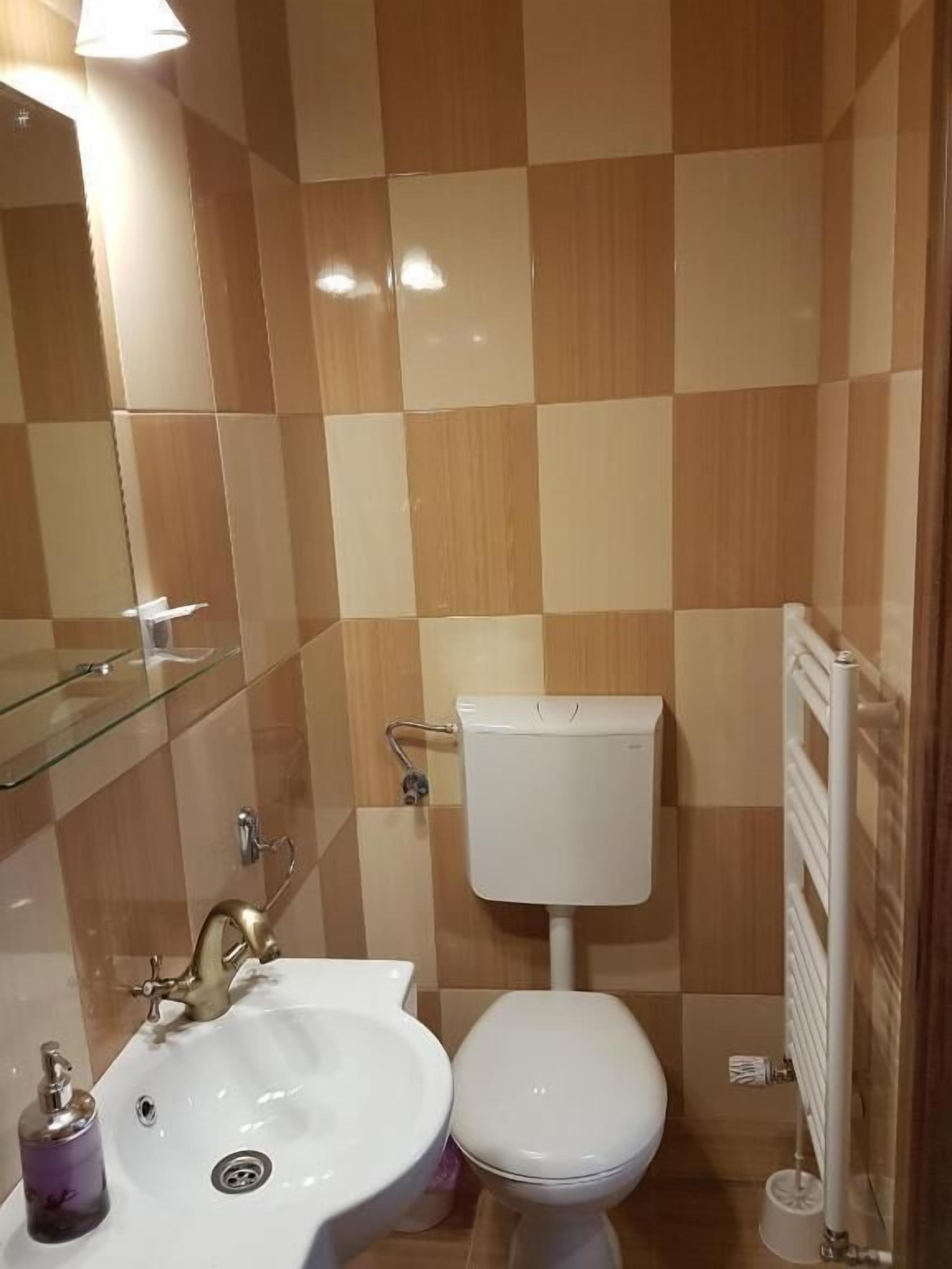 Un bagno con lavandino, water e box doccia in vetro.