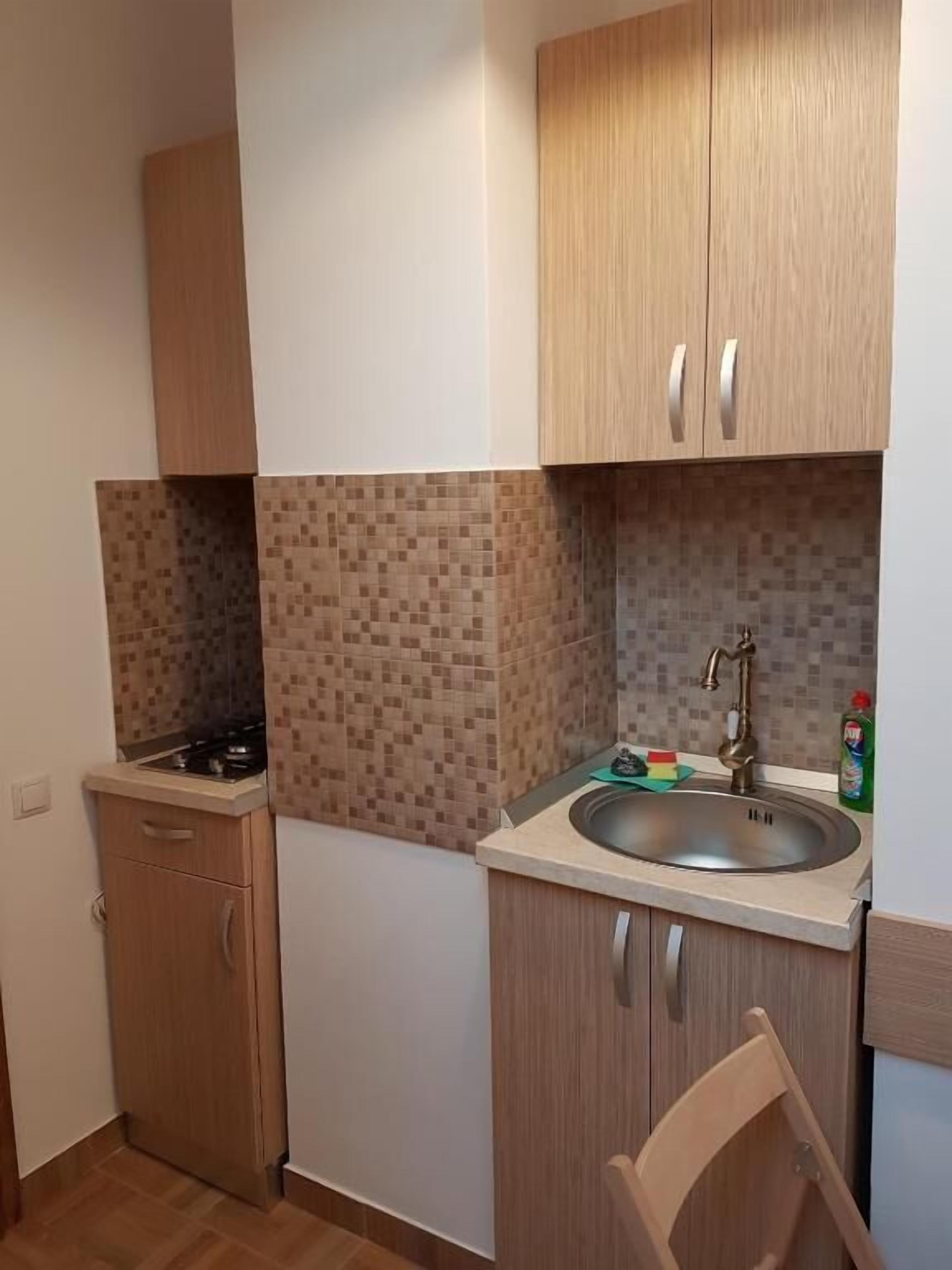 A compact kitchen with a sink, stove, and cabinets.