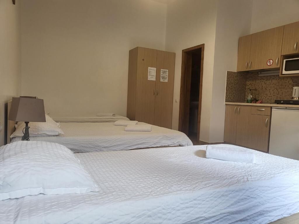 Une chambre d’hôtel avec deux lits, une kitchenette et une porte donnant sur une autre pièce.