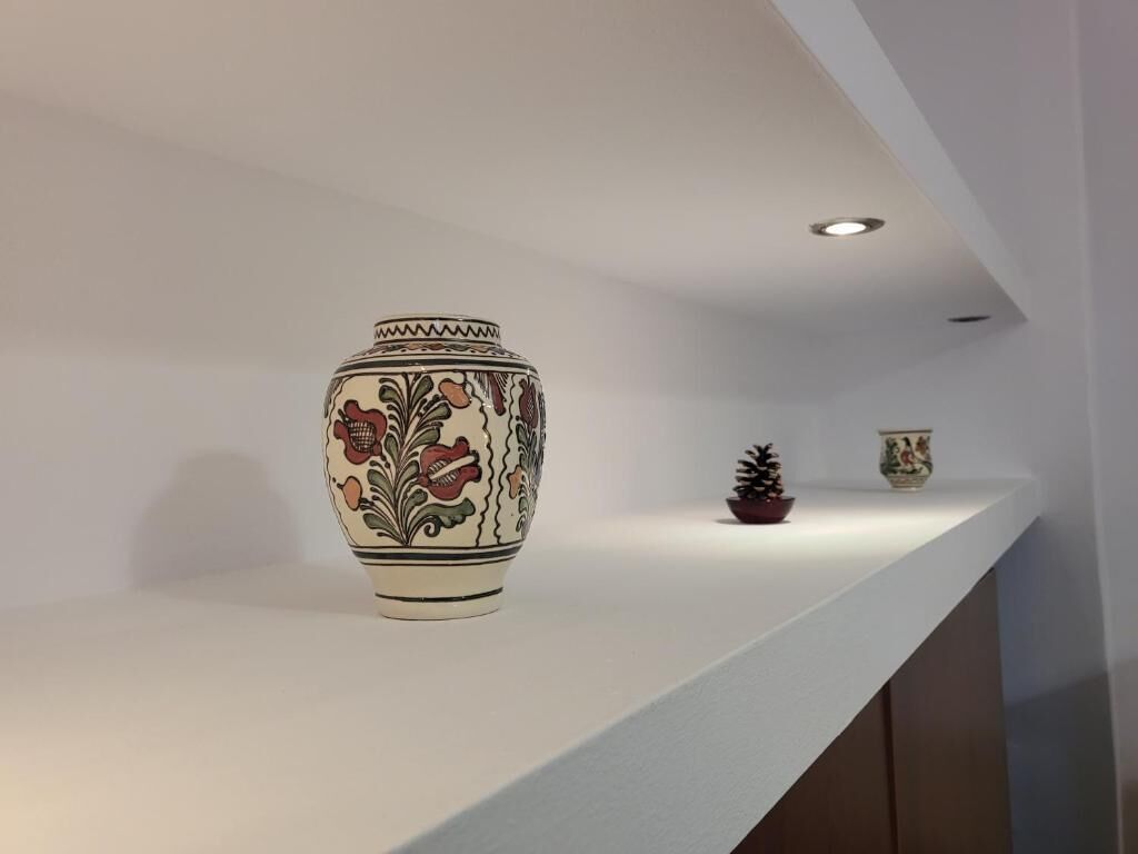 A white shelf with a decorative vase and a small potted plant.
