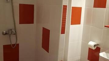 Bagno con doccia, wc e lavandino, rivestito con piastrelle rosse e bianche.