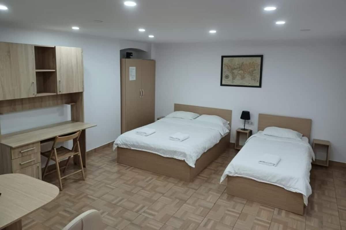 Een kamer met twee bedden, een bureau, een stoel en een kledingkast.