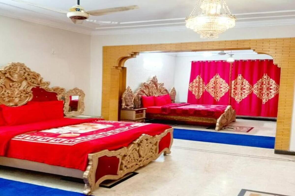 A room with two ornate beds, a chandelier, and a ceiling fan.