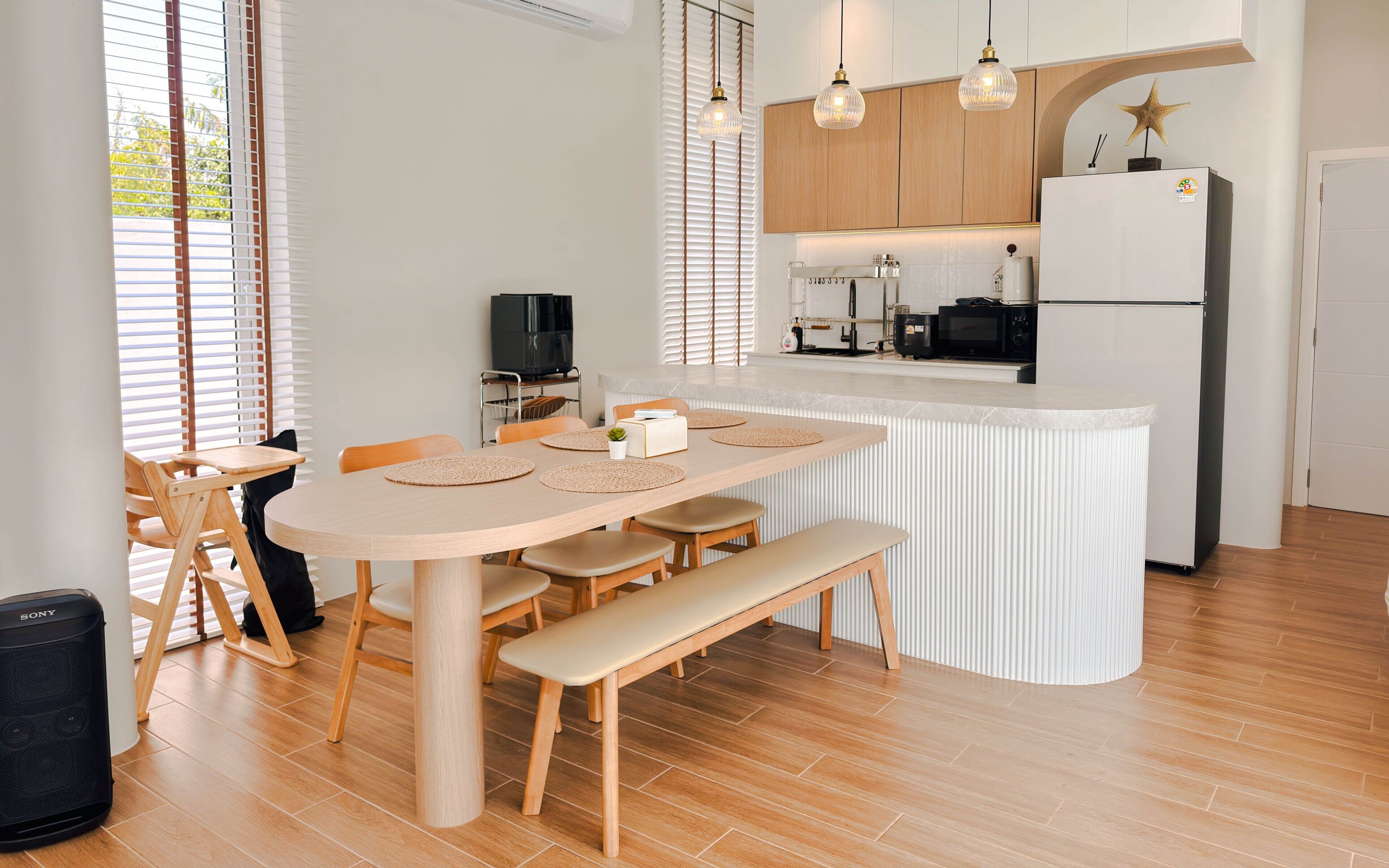 Cocina moderna con una isla central, sillas de madera y un banco.
