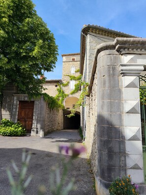 Un carreró estret amb un edifici de pedra, una porta de fusta i un arbre.