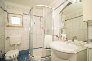 A bathroom with a toilet, shower, sink, and a large mirror. - Comfort apartment for 4 people with balcony and parking space (Crikvenica)