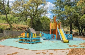Ein Spielplatz mit Rutsche, Klettergerüsten und einer kleinen Spielhaus-ähnlichen Fläche.