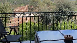 En balkong med utsikt över ett kustlandskap, inklusive terrasserade byggnader och grönområden.