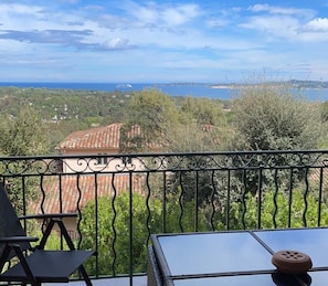 Ein Balkon mit Blick auf eine Küstenlandschaft, darunter Terrassenhäuser und Grünfl ächen.