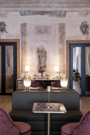 A hotel lobby with a central seating area, a reception desk, and a decorative wall with classical reliefs. - Palazzo De Polo (Venice)