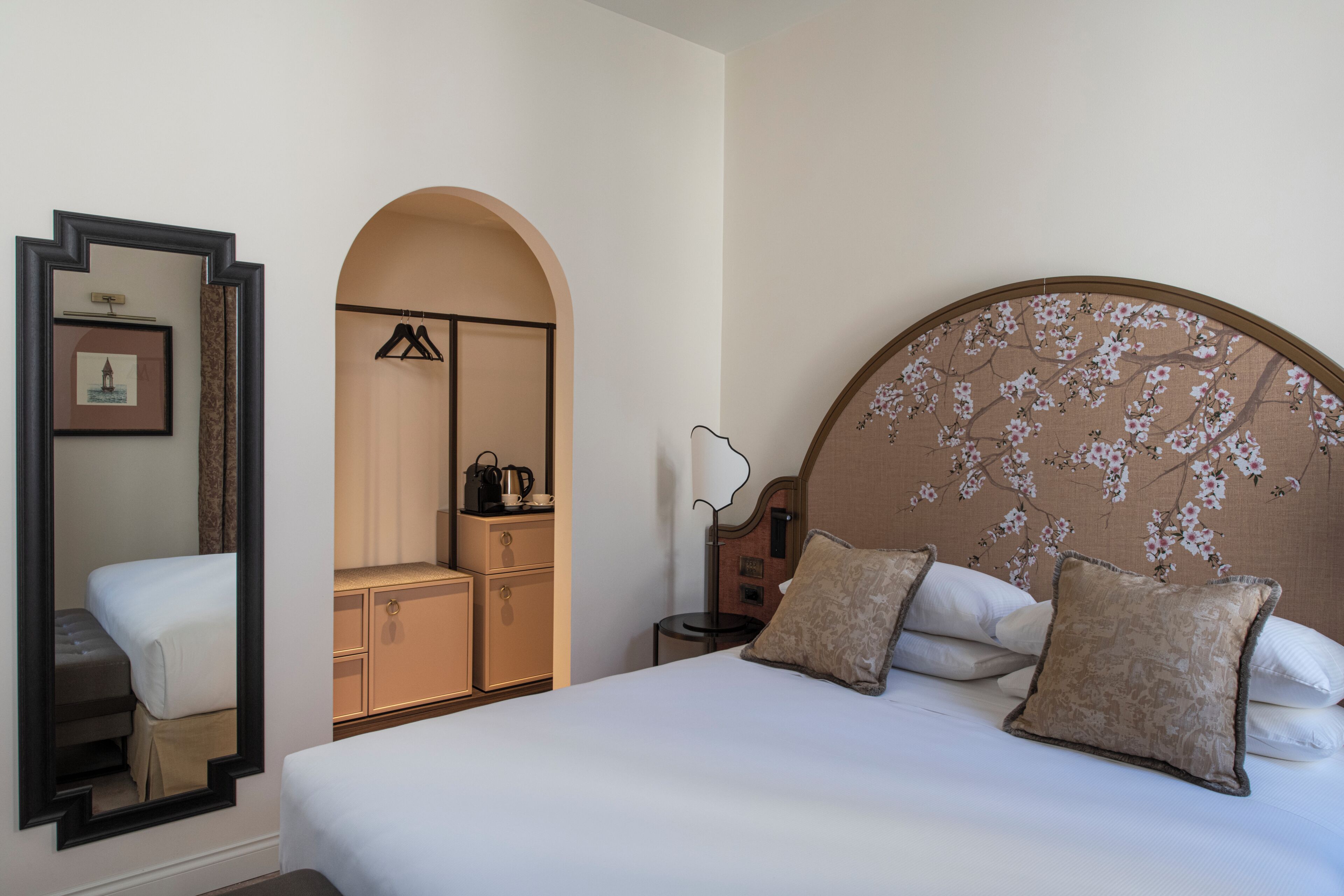 Ein Hotelzimmer mit einem großen Bett, einem Kleiderschrank, einem Spiegel und einem Nachttisch.