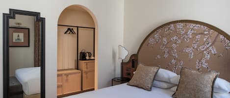 Una camera d'albergo con un letto grande, un armadio, uno specchio e un comodino.