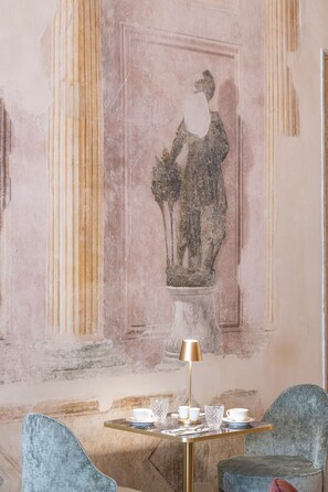 A room with a marble table set for dining, a gold lamp, and a classical fresco on the wall. - Palazzo De Polo (Venice)
