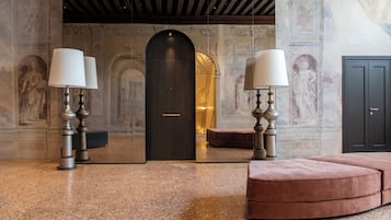 Eine Lobby mit Marmorboden, einer dunklen Holztür und einer Sitzecke mit einer pinkfarbenen Polsterbank.