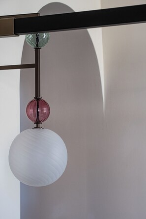 Una lámpara de techo con pantalla blanca y globo rosa.