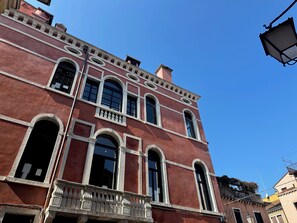 A red building with arched windows and a balcony.