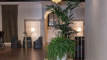 A modern lobby with a high ceiling, a central chandelier, and a reception desk.
