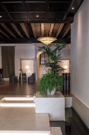 A modern lobby with a high ceiling, a central chandelier, and a reception desk. - Palazzo De Polo (Venice)