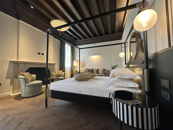 A four-poster bed with a black frame, a round mirror above it, and a black and white striped side table.