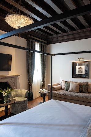 Una habitación de hotel con cama, sofá, televisor, chimenea y candelabro.