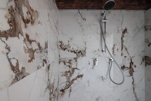 Ducha con cabezal de ducha de mano y llave de control en la pared.